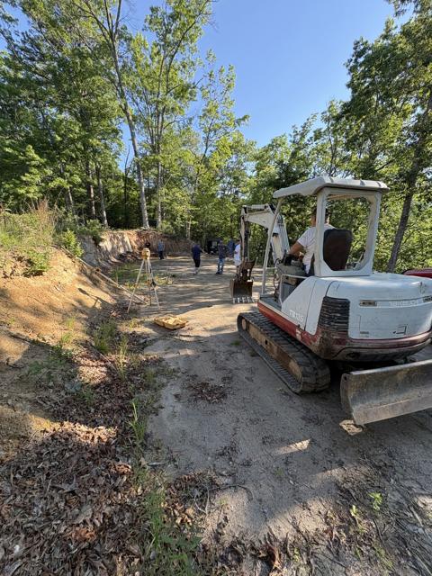 Squaring up the foundation. The crew sets the lines while the excavator stands by.